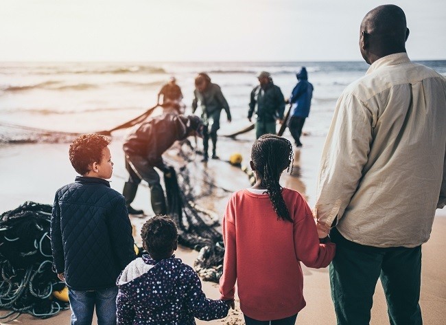 children with adult male in front of the sea