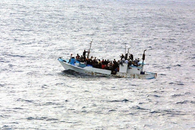 types of migration, forced migration, people migrating in a boat.